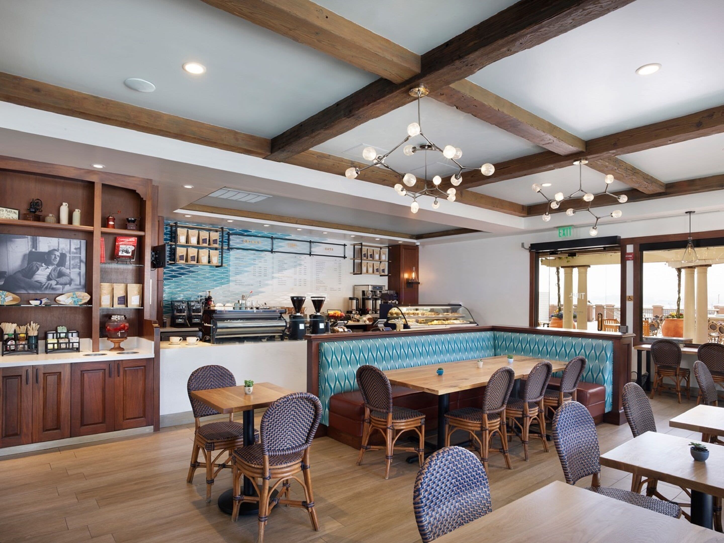 A restaurant with wooden beams, a bar area, and seating with wicker chairs.