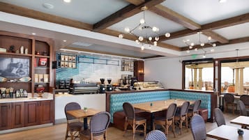 A restaurant with wooden beams, a bar area, and seating with wicker chairs.