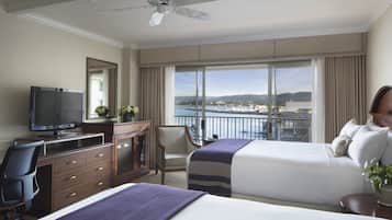 Ett hotellrum med två sängar, en TV, ett skrivbord och utsikt över havet.
