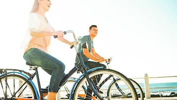 Dos personas pedaleando en bicicletas estáticas a lo largo del paseo marítimo.