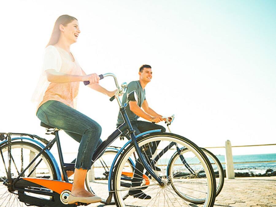 Twee personen fietsen op een strandboulevard.