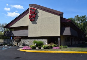 Un Red Roof Inn con fachada de piedra, entrada visible y estacionamiento con espacios reservados para discapacitados.