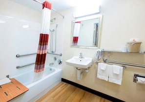 A bathroom with a bathtub, a sink, a mirror, and a shower.