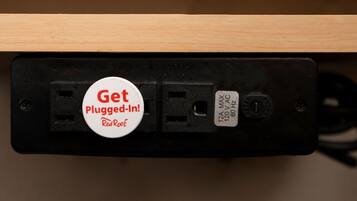 A power outlet with a plug-in reminder sign and an electrical specification label.