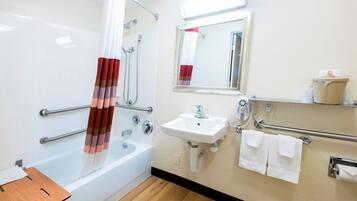 Un baño con bañera, lavamanos, espejo y ducha con cortina.
