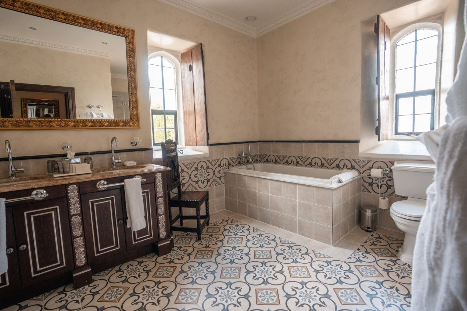 Un baño con un espejo grande, una bañera, un inodoro y un lavamanos.