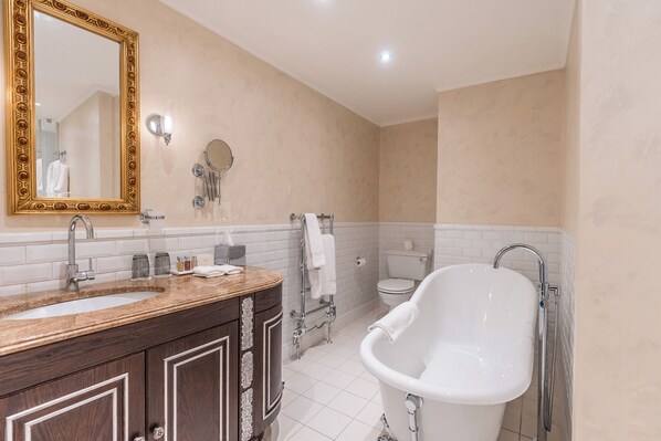 A bathroom with a large mirror, two sinks, a bathtub, and a toilet.