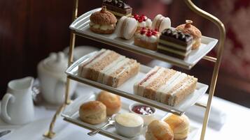 A three-tiered dessert display with various pastries and sandwiches.
