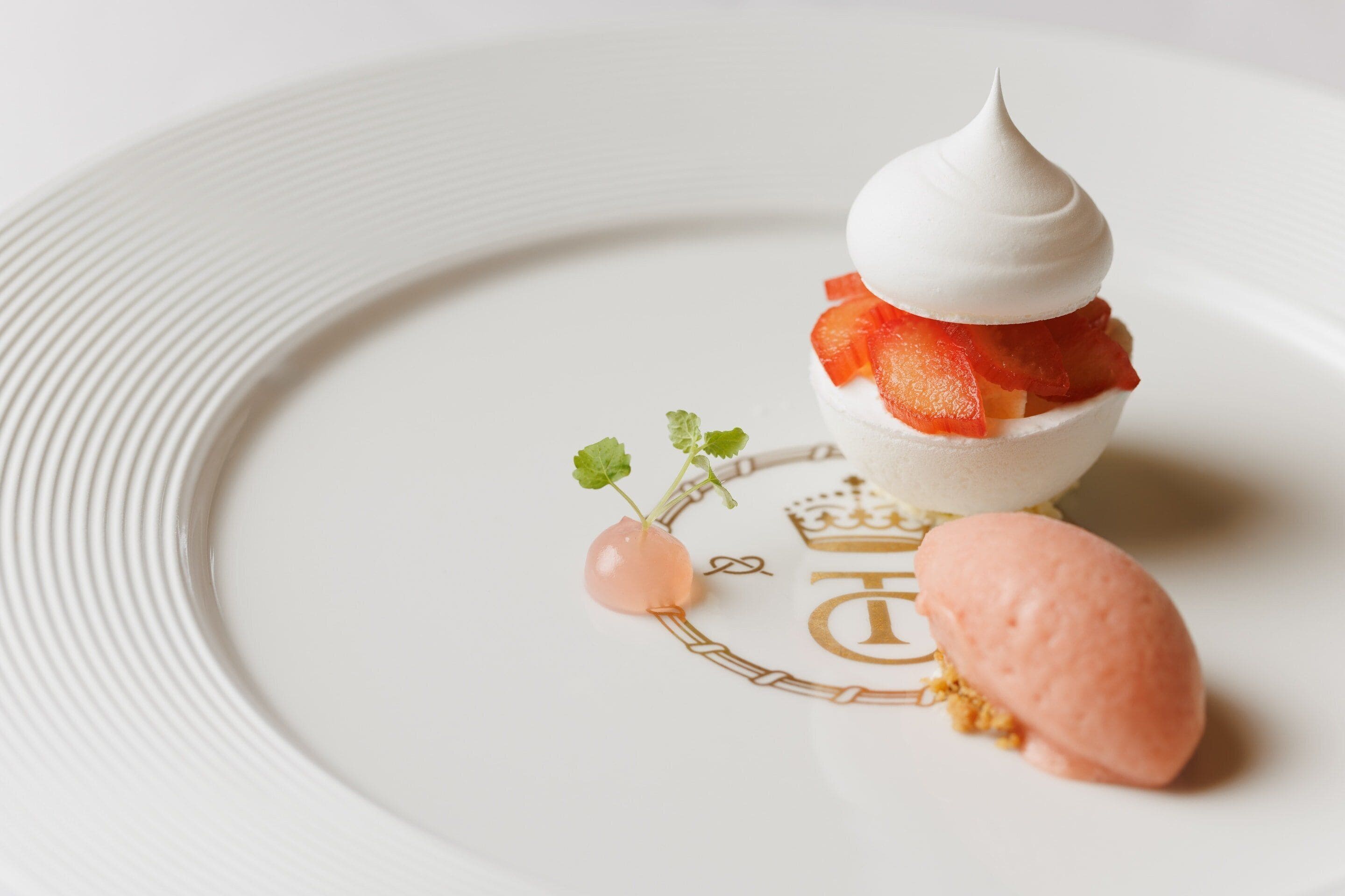 Un postre sobre un plato blanco con un emblema dorado.
