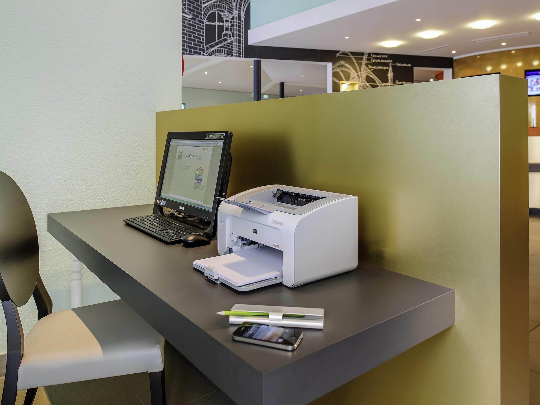 Un bureau avec un ordinateur portable, une imprimante, un téléphone intelligent et un crayon.