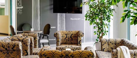 Un interior moderno con muebles estampados, un televisor de pantalla plana y una planta en maceta.