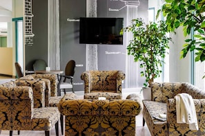 Un interior moderno con muebles estampados, un televisor de pantalla plana y una planta en maceta.