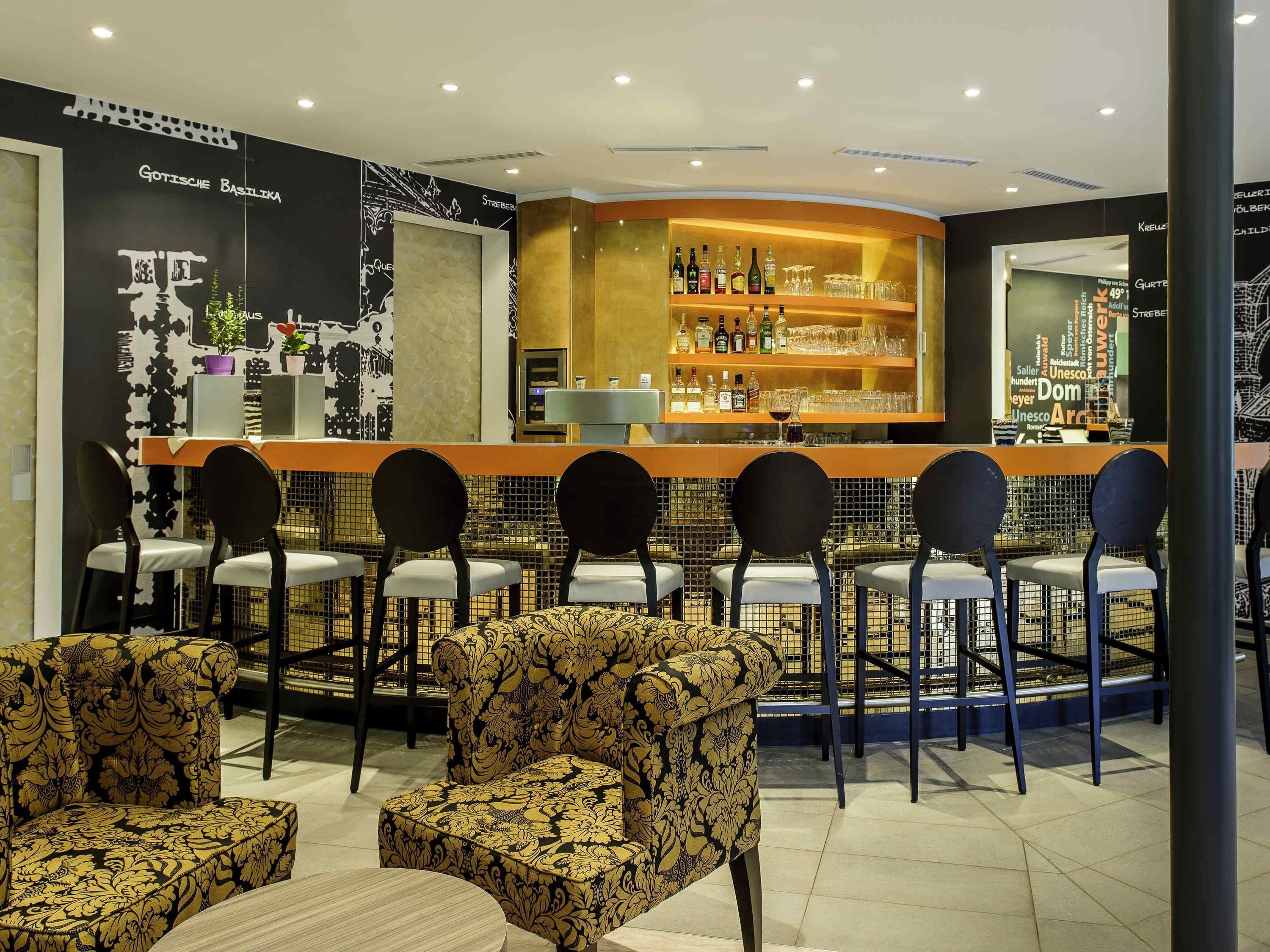 Un espace bar avec un comptoir, des chaises et un canapé à motifs.