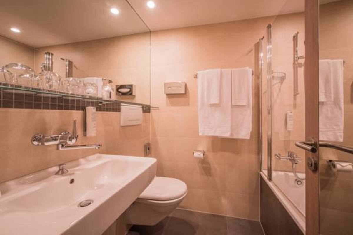 A modern bathroom with a sink, toilet, and glass-enclosed shower.