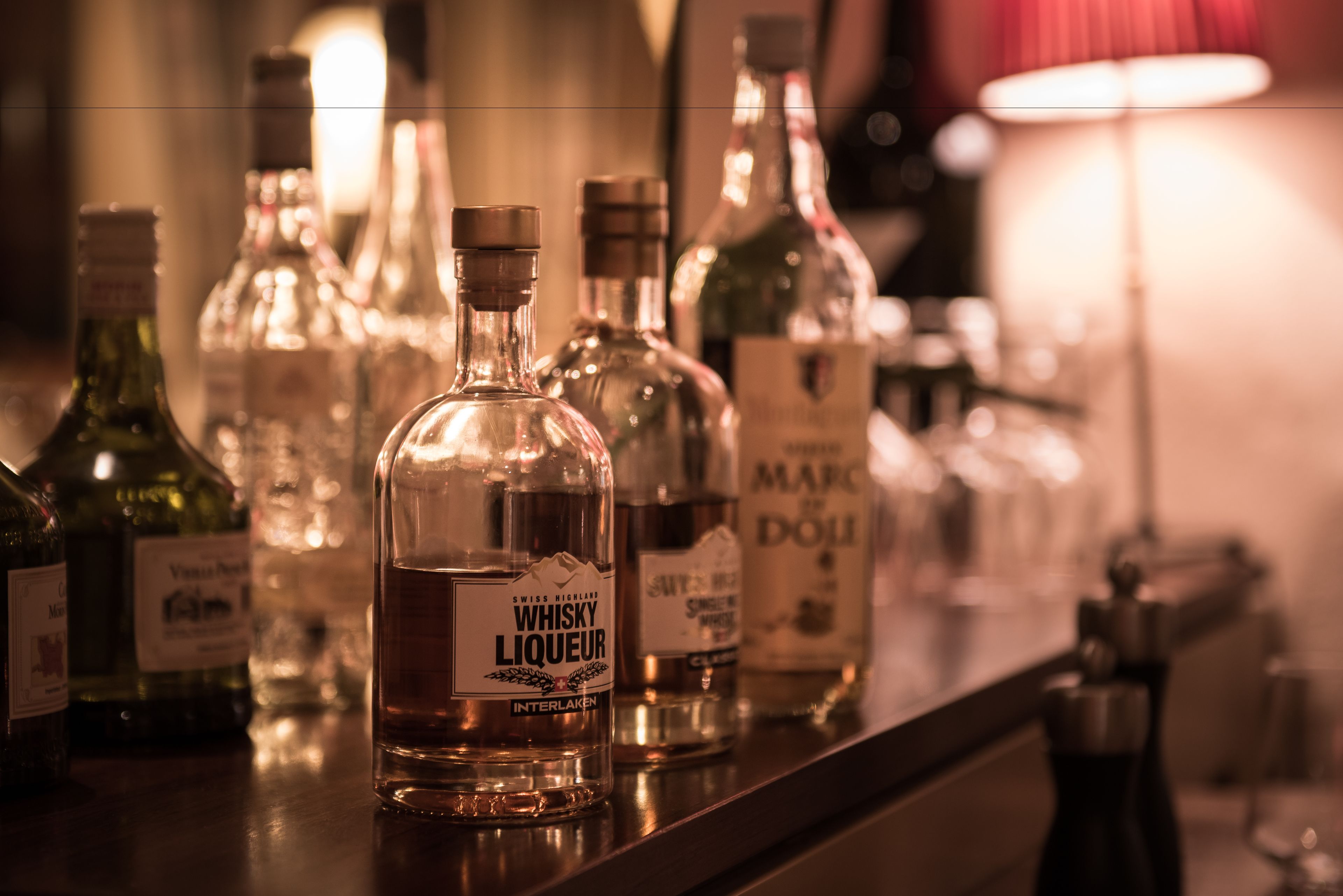Eine Bar mit einer Theke und verschiedenen Spirituosenflaschen, darunter eine auffällig präsentierte Flasche Schweizer Whisky.