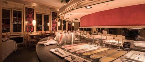 A buffet setup with various food stations, a counter with utensils, and a seating area with tables and chairs.
