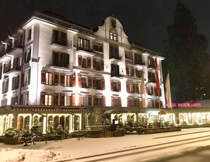 Un hotel de varios pisos con un estilo arquitectónico europeo clásico, con balcones y una entrada destacada con un cartel.