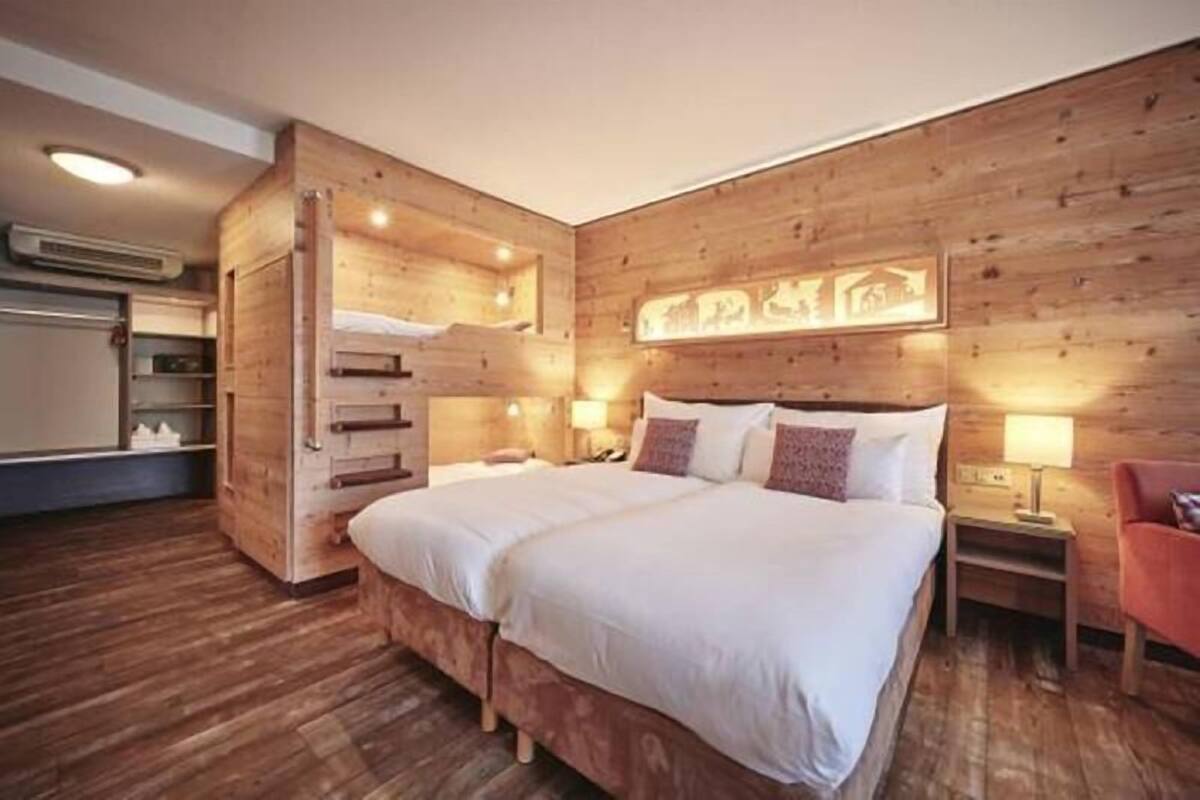 A wooden-paneled room with a bed, bedside tables, and a wall-mounted artwork.