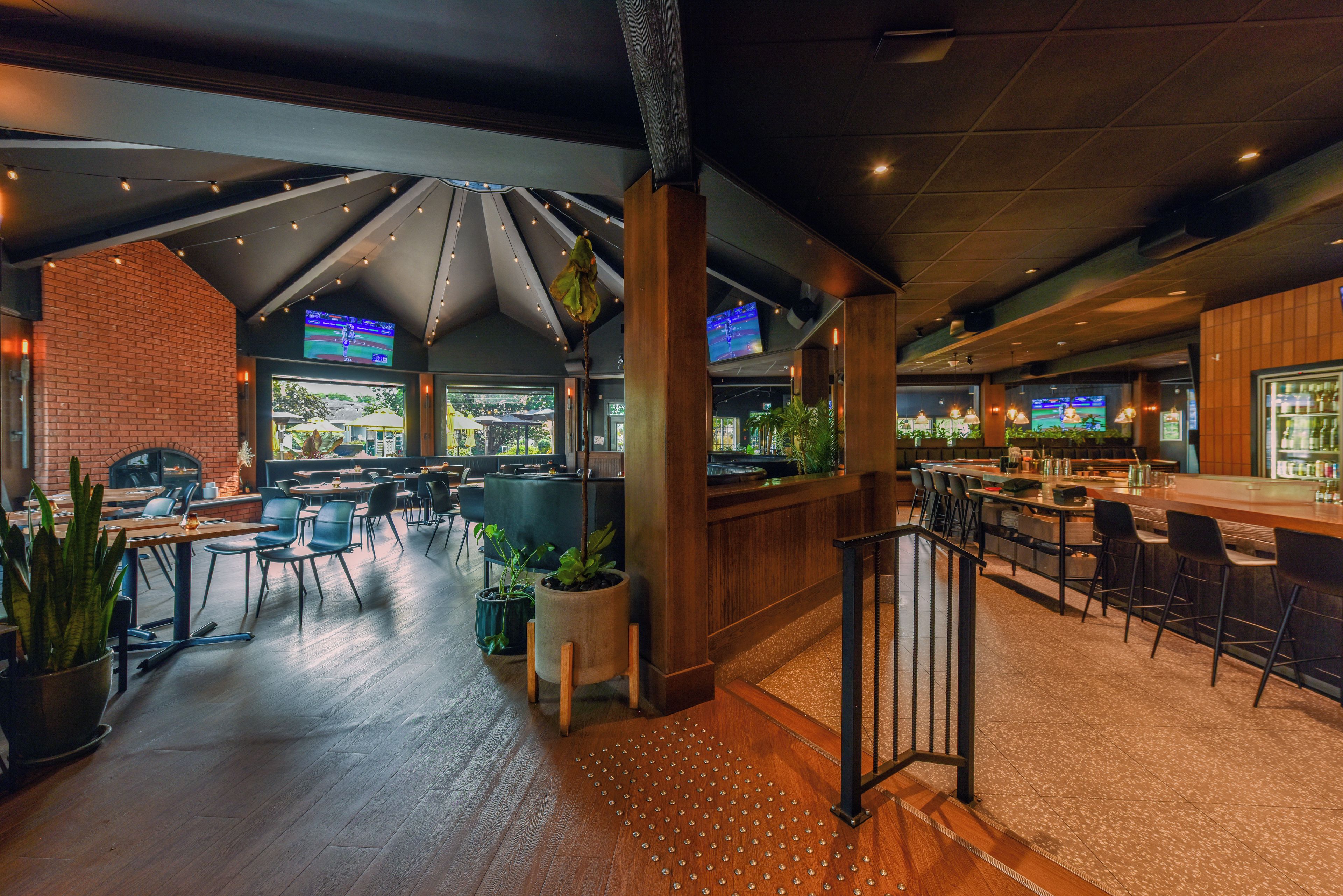 A spacious indoor area with multiple seating arrangements, including tables and chairs, and a bar area with stools.