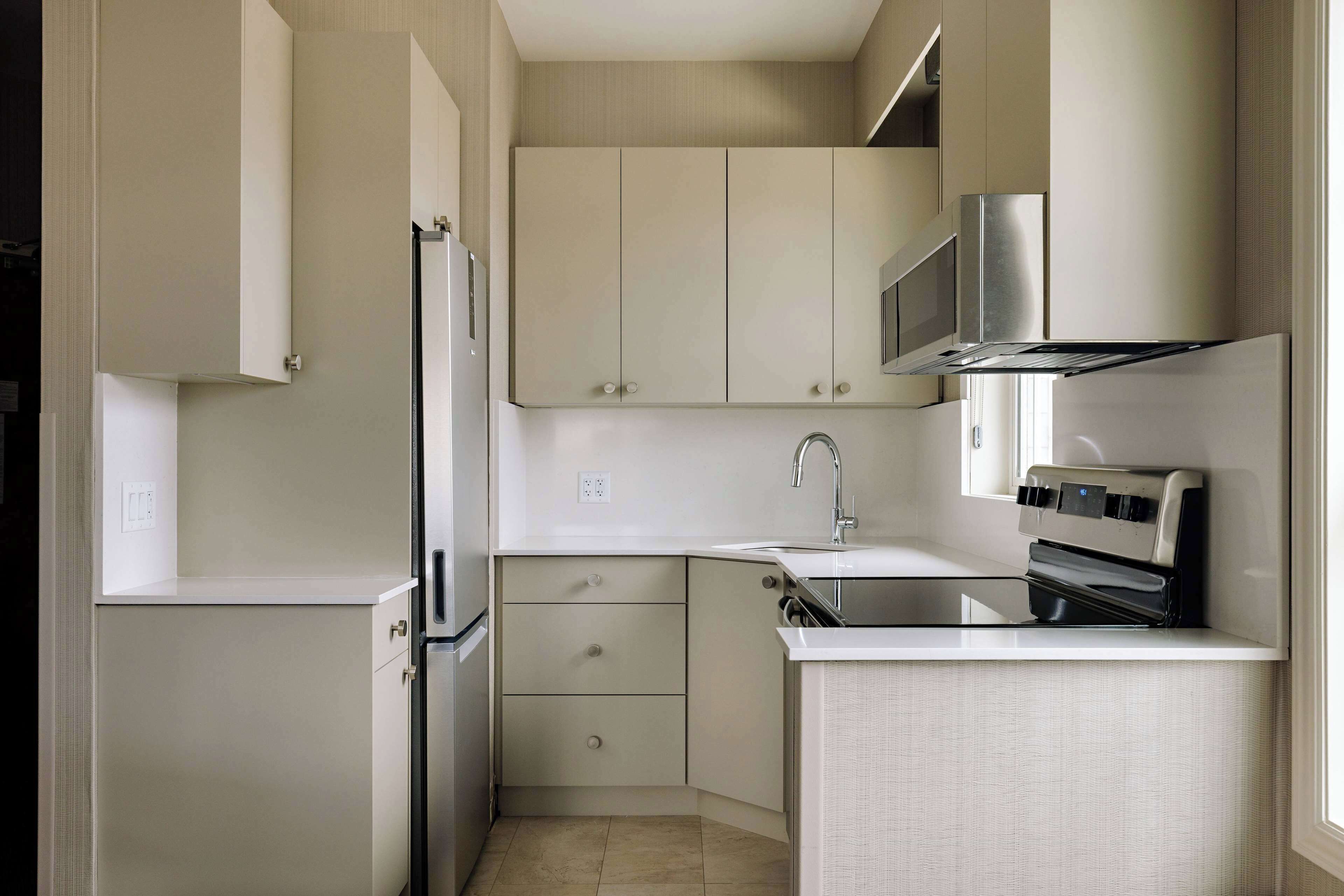 A compact kitchen with a refrigerator, microwave, stove, and sink.