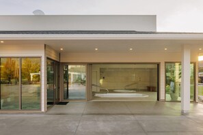Un edificio moderno con entrada de cristal, una piscina interior visible y una escalera que conduce a un nivel superior.