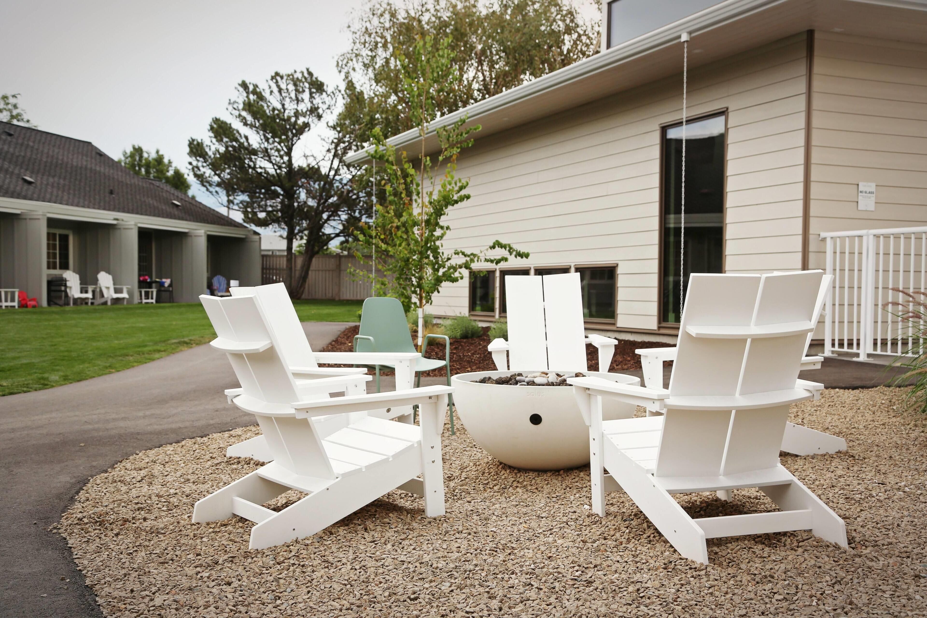 An outdoor seating area with Adirondack chairs and a fire pit.