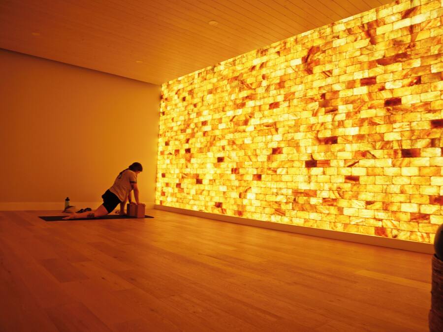 A person performing a yoga pose on a mat in a room with a wooden floor and a wall with a textured pattern.