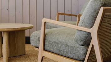A wooden chair with a woven backrest and a round wooden table.