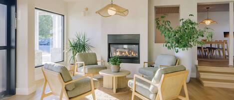 A modern living room with a fireplace, comfortable seating, and a dining area.