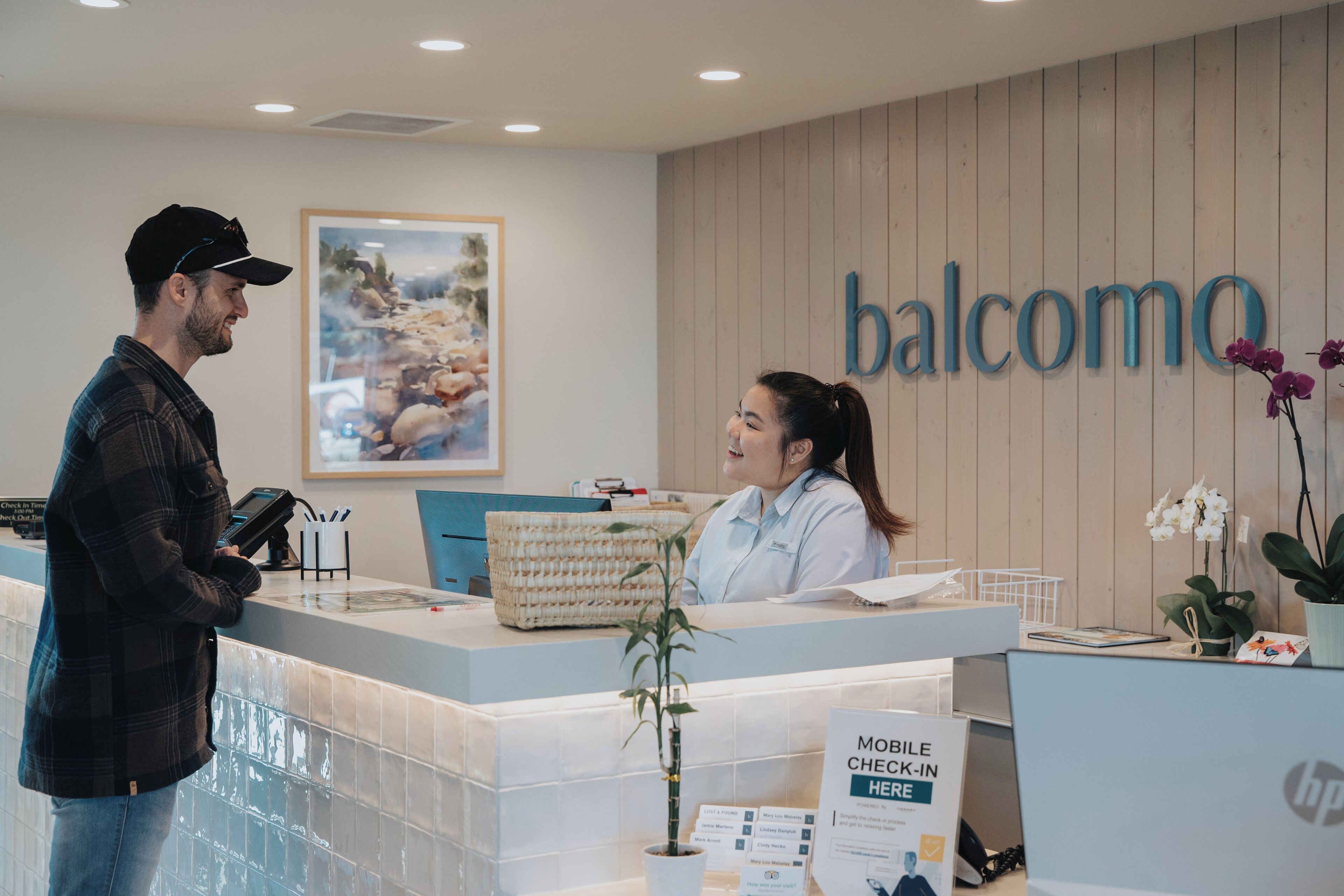 Una recepción con un letrero que dice "balcomo", un letrero para registro móvil y un cuadro en la pared.