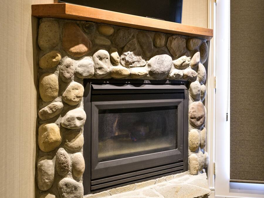 A stone fireplace with a flat-screen TV mounted above it.