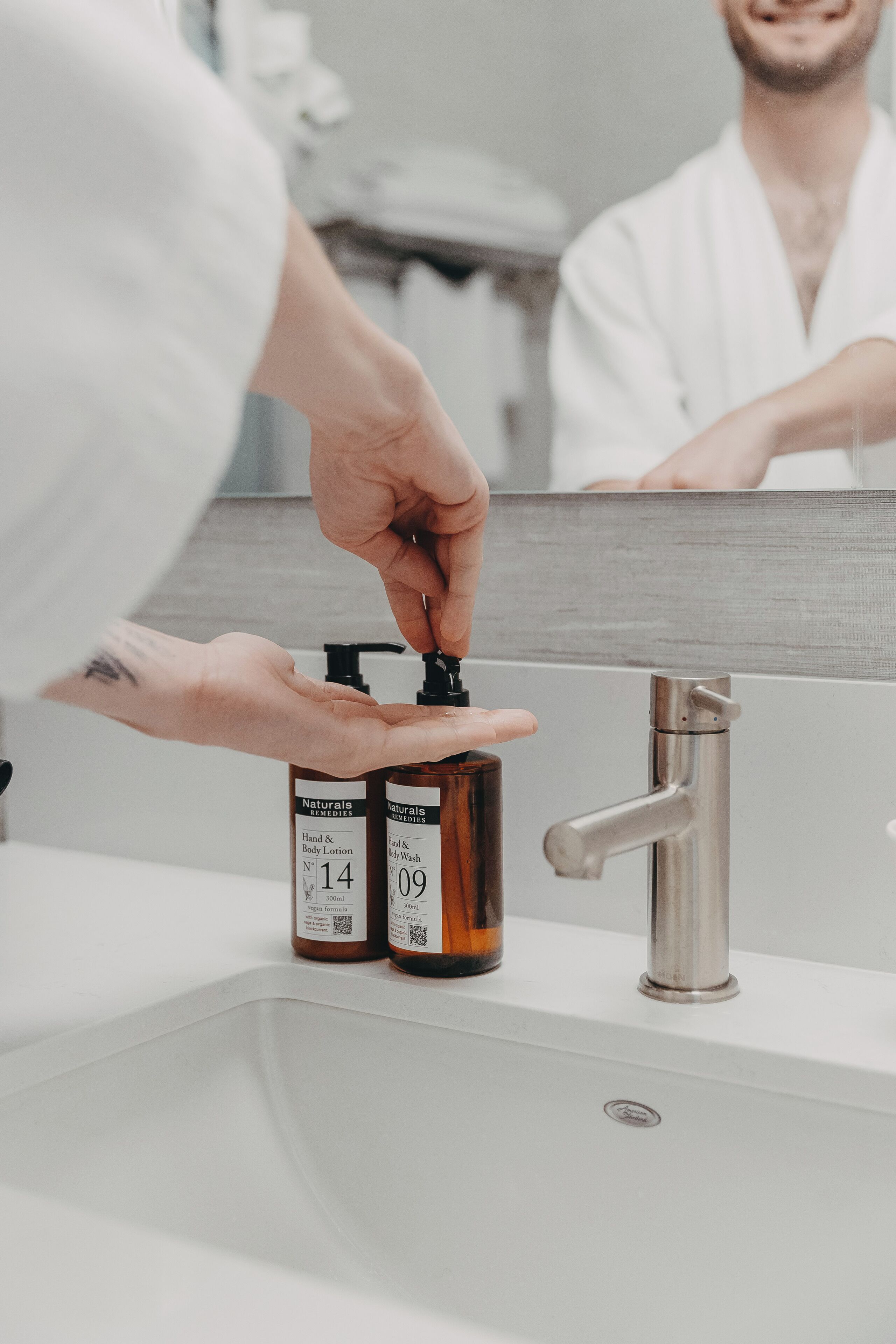 A bathroom sink with two bottles of hand and body lotion.