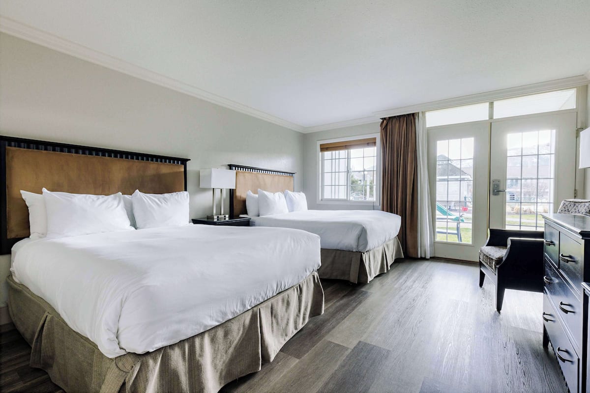 A hotel room with two beds, a desk, and a chair.