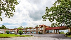 Un motel avec un toit rouge, plusieurs étages et un parking.