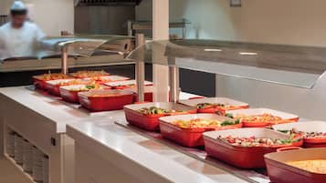 A buffet line with various food dishes in red trays.