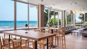 A spacious room with a large wooden table and chairs, a sofa, and a view of the ocean. - Sol Marbella Estepona - Atalaya Park (Estepona)