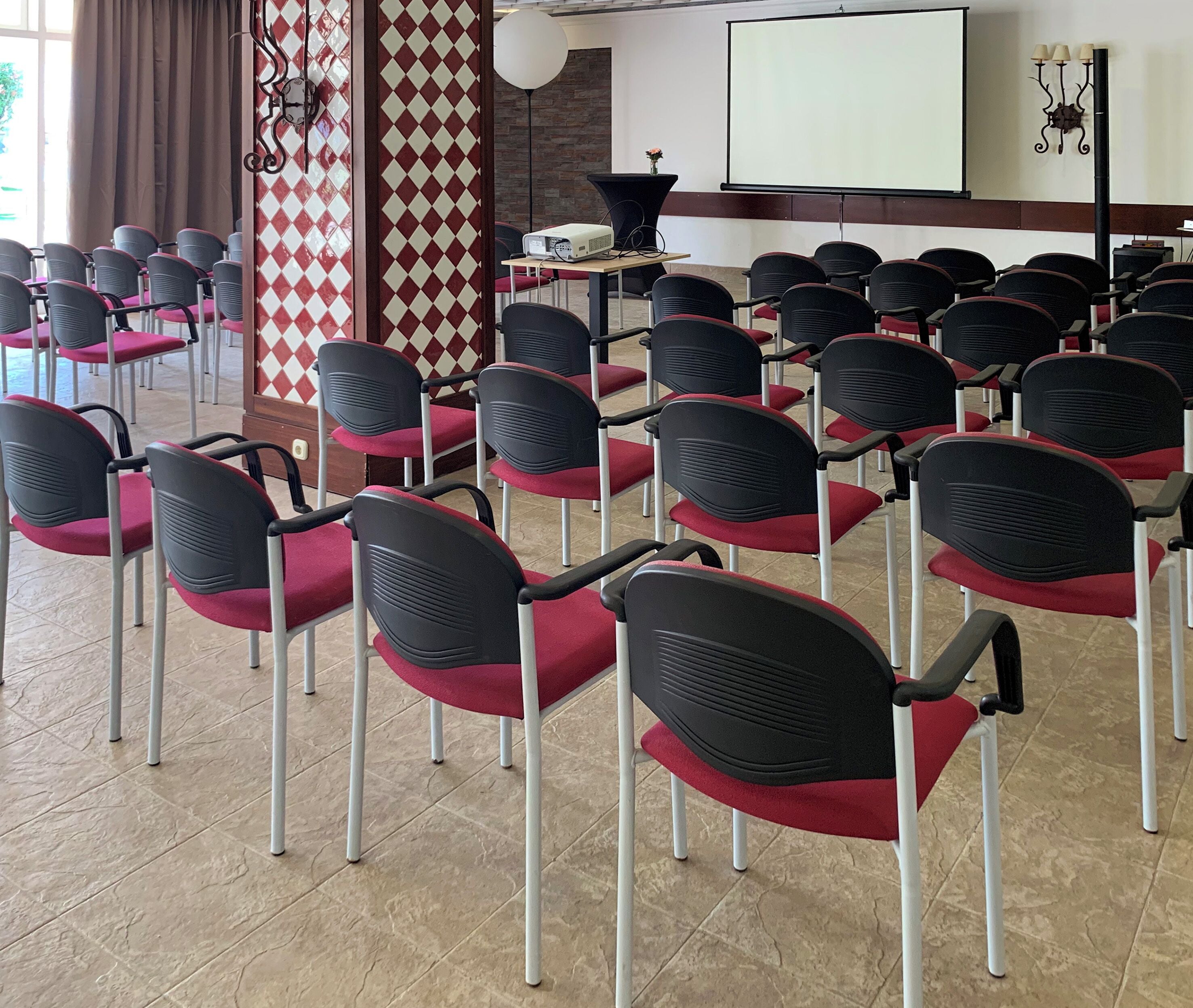 Une salle de conférence avec des rangées de chaises, un projecteur et un écran.