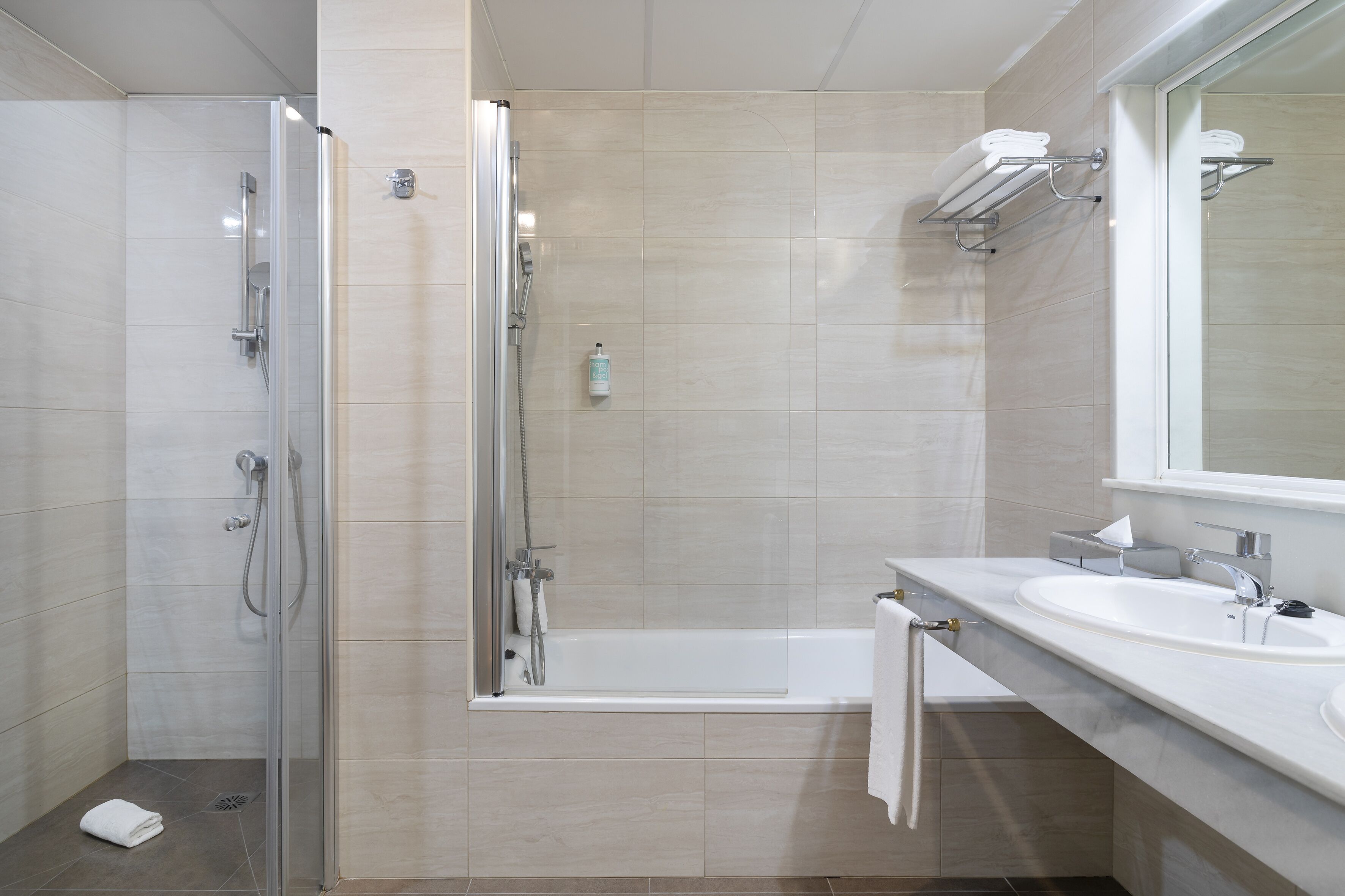 A modern bathroom with a glass-enclosed shower, a bathtub, and a vanity with a sink and mirror.