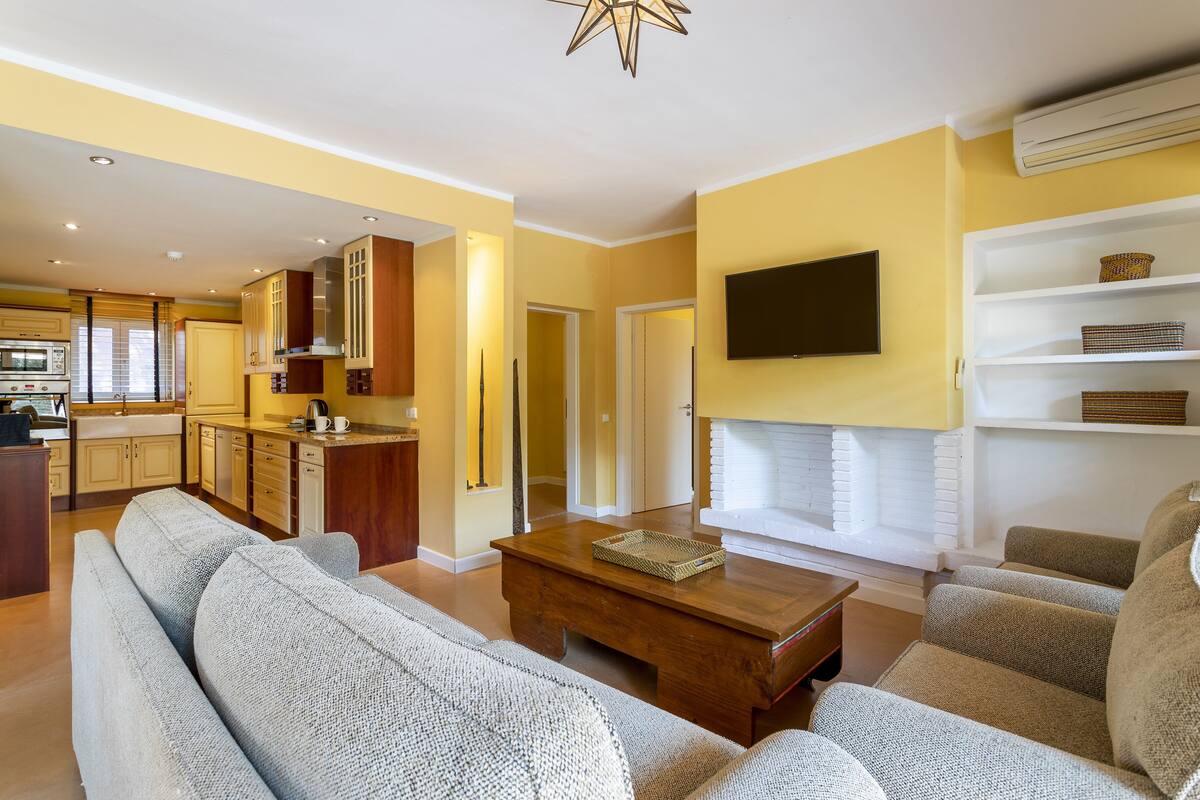 Una sala de estar moderna con un conjunto de sofá, una mesa de centro de madera y un televisor de pantalla plana montado en la pared.