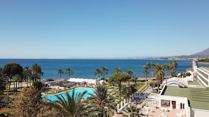A resort with a pool, palm trees, and a view of the ocean. - Sol Marbella Estepona - Atalaya Park (Estepona)