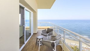 A balcony with a view of the ocean, a chair, a small table, and a sliding glass door. - Sol Marbella Estepona - Atalaya Park (Estepona)