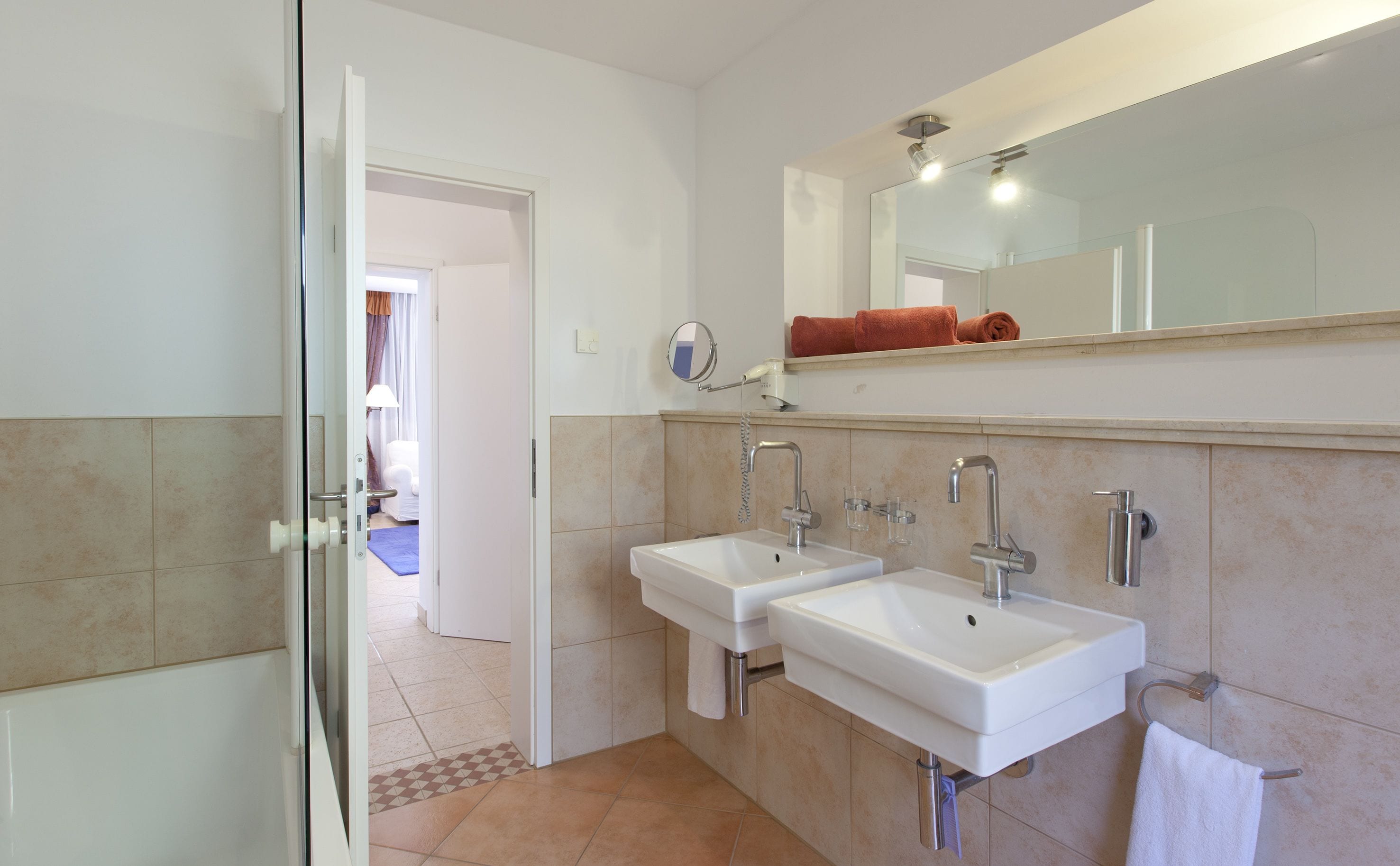 A bathroom with two sinks, a mirror, and a towel rack.