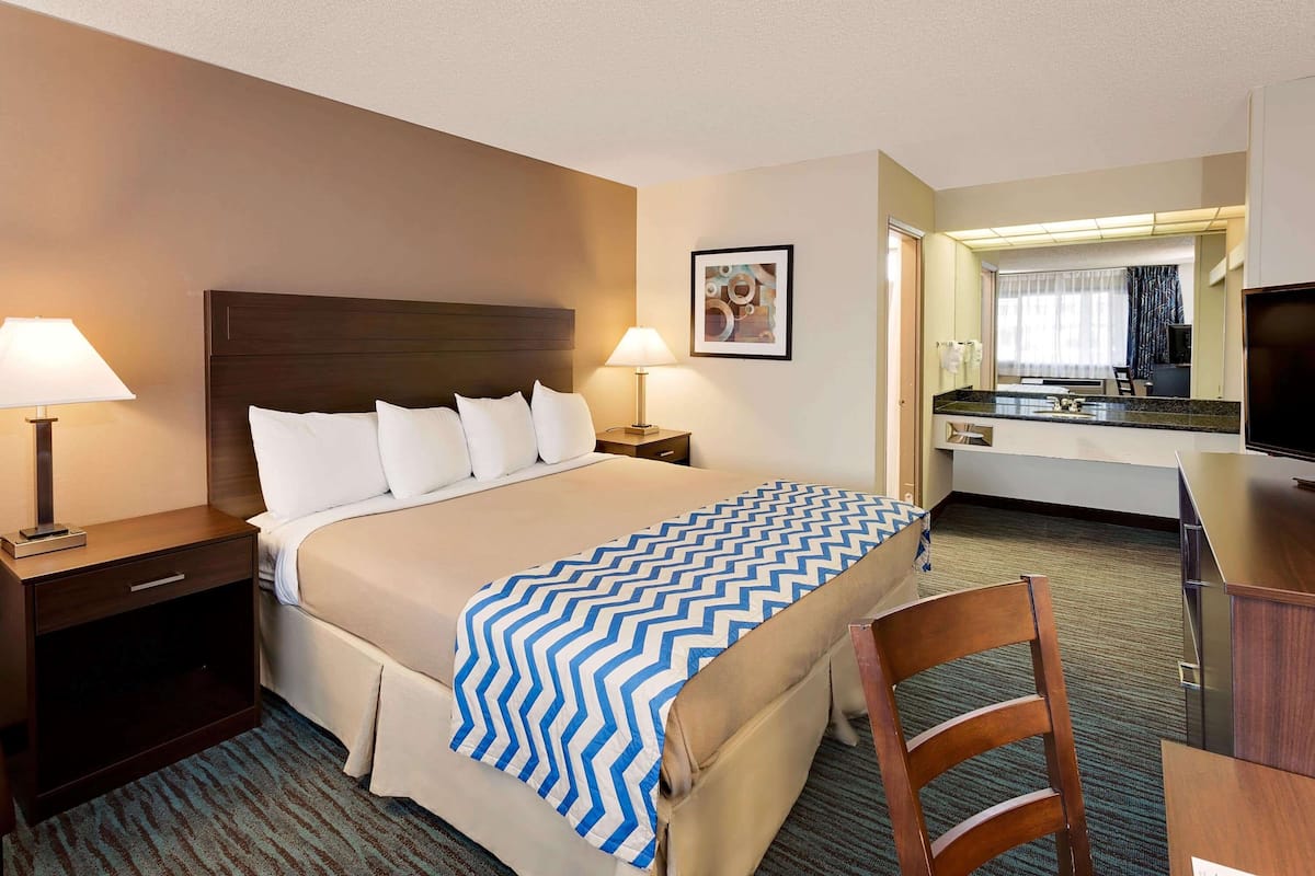 A hotel room with a bed, bedside tables, a desk, and a chair.