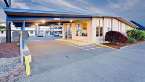 A motel with a covered entrance, a parking lot, and a building with multiple floors.