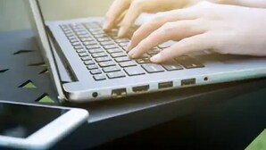 A laptop on a desk with a smartphone beside it.