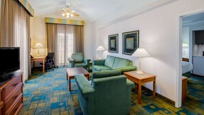 A hotel room with a TV, green sofas, a desk, and a ceiling fan. - La Quinta Inn by Wyndham Lufkin (Lufkin)