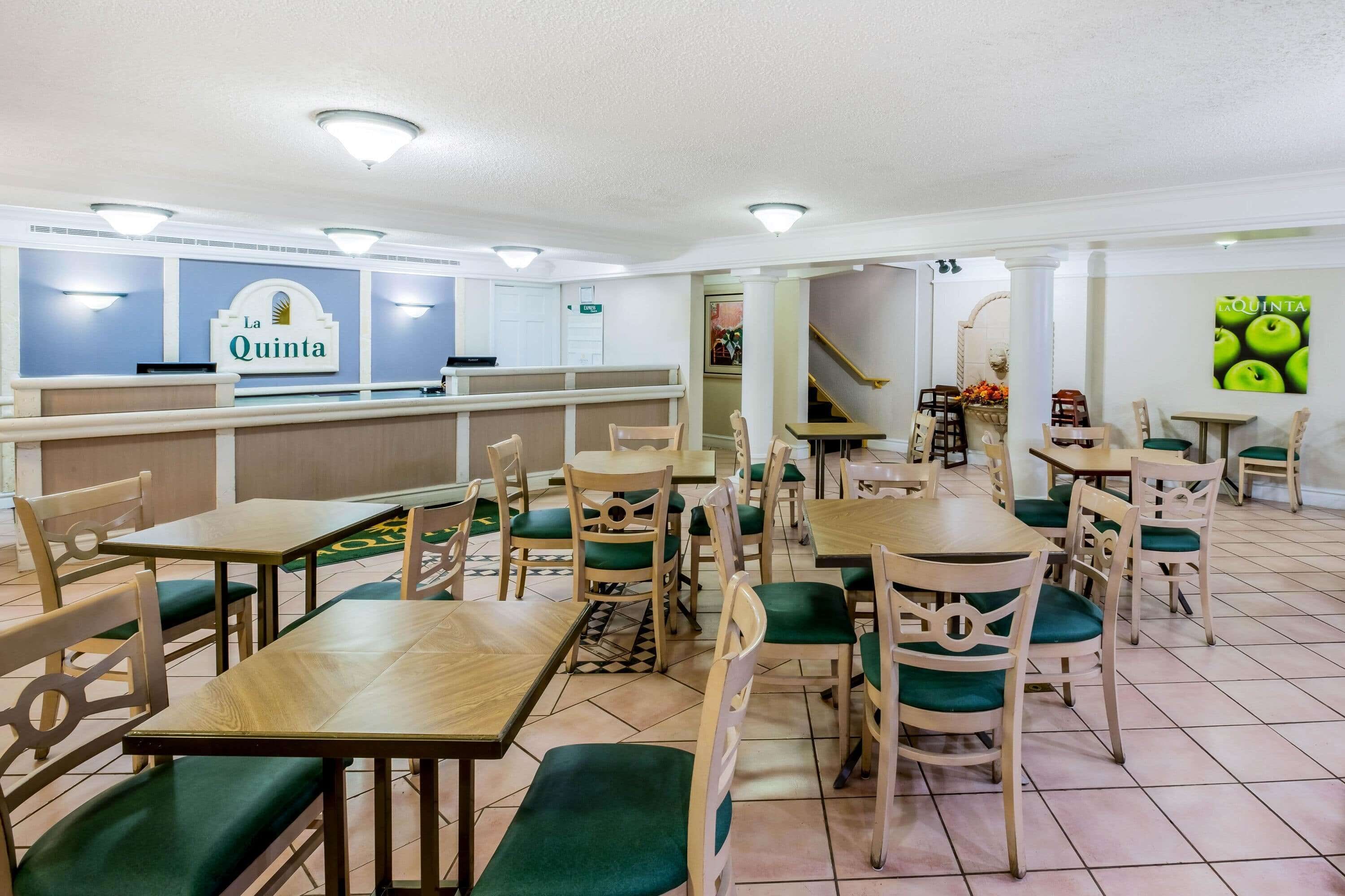 A restaurant with a 'La Quinta' sign, wooden tables and chairs, and a tiled floor.