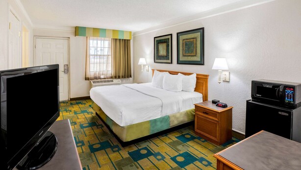 A hotel room with a bed, a television, a microwave, and a desk. - La Quinta Inn by Wyndham Lufkin (Lufkin)