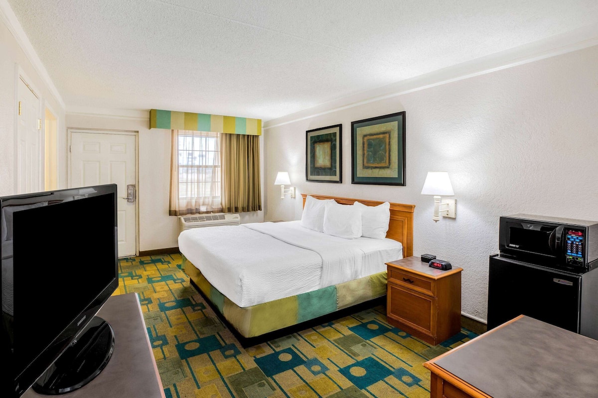 A hotel room with a bed, a television, a microwave, and a desk.