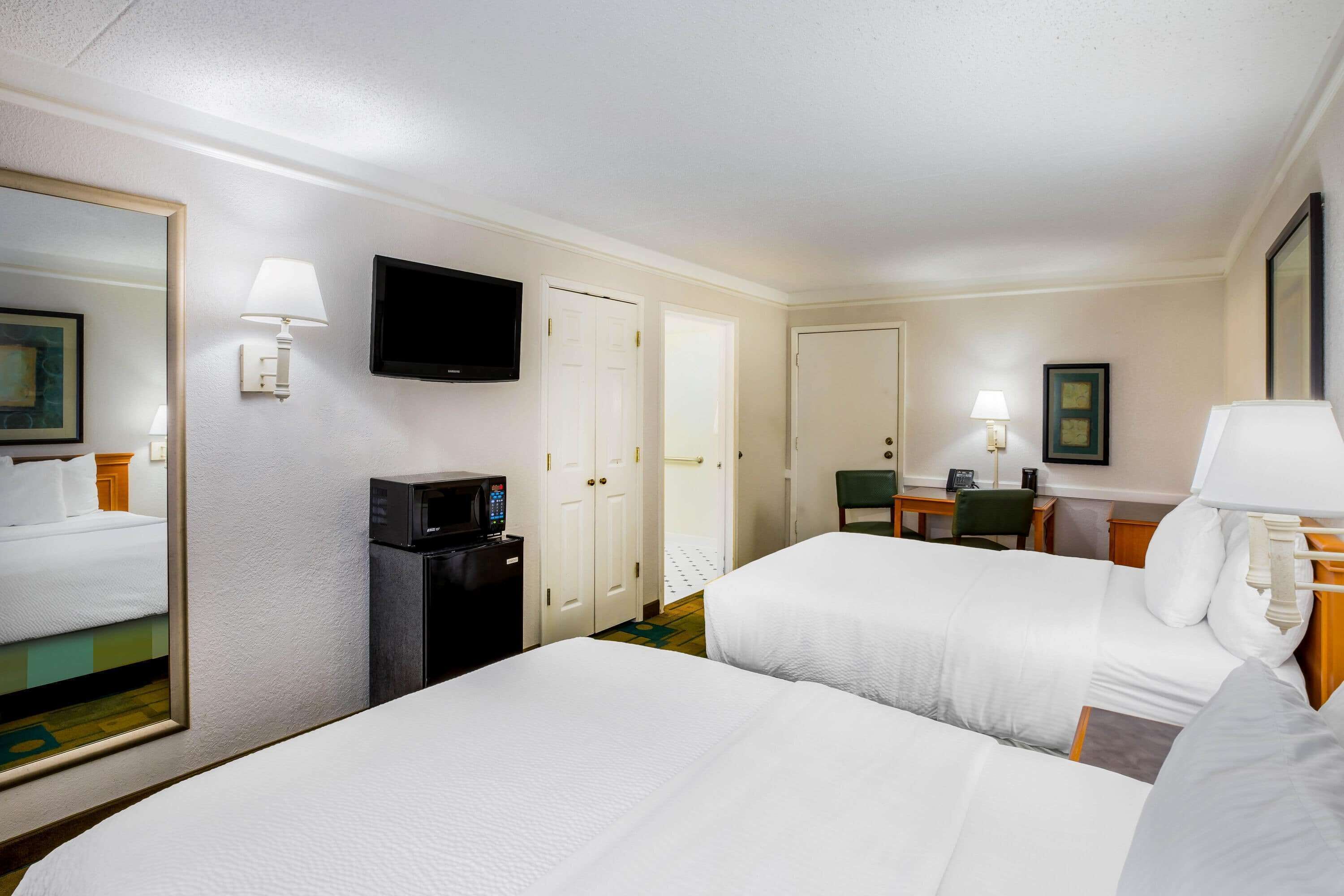 Een hotelkamer met twee bedden, een televisie, een bureau met stoel en een koffieapparaat.